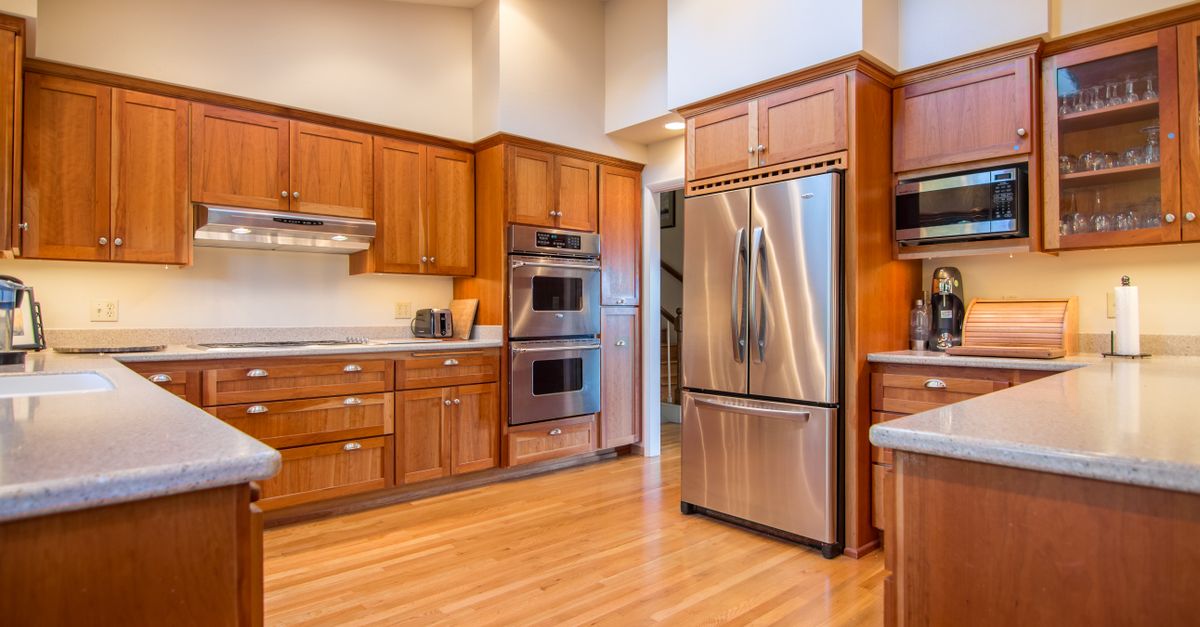 Moderne keuken met houten kastjes en een dubbele roestvrijstalen oven ingebouwd in de kastenwand.
