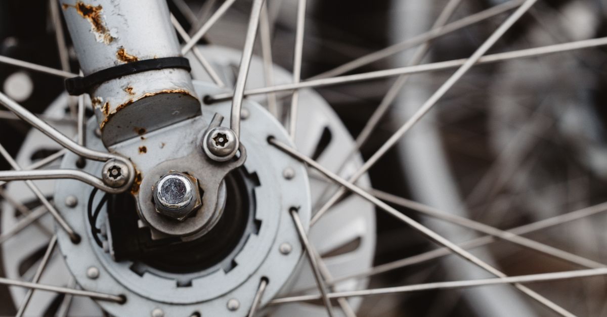 Close-up van een verroeste fietsnaaf en vork met spaken van een wiel.