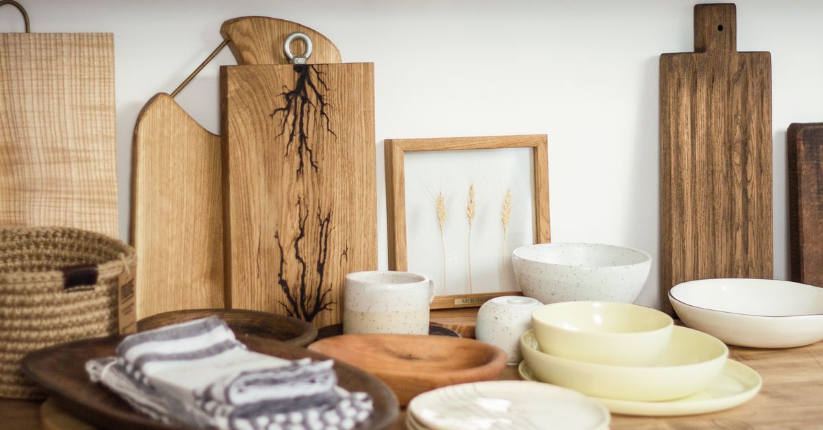 Houten snijplanken staan verticaal opgesteld tegen de muur naast kommen en een fotolijstje op een houten plank in de keuken.