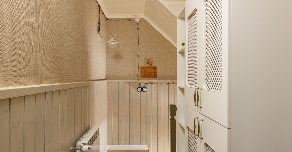 Smalle gang met een witte kast met rasterdeuren voor opbergruimte naast houten lambrisering