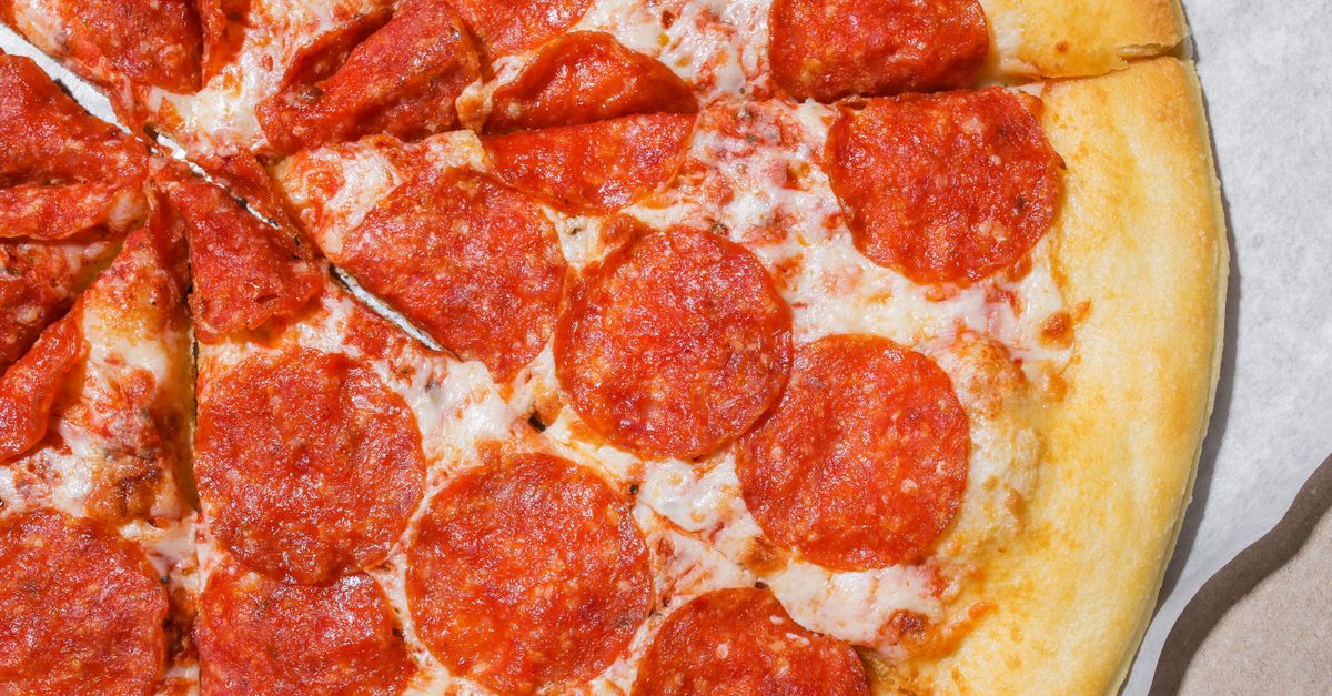 Bovenaanzicht van een pepperonipizza met een goudbruine, krokante korst, in punten gesneden.