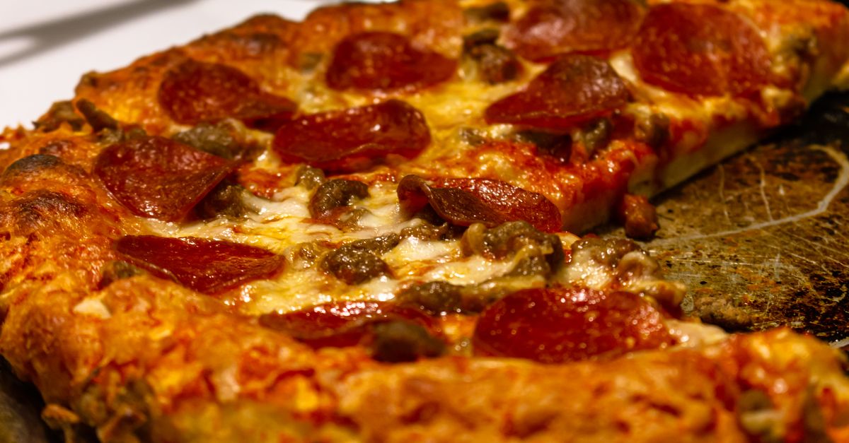 Close-up van een pepperoni pizza met een goudbruine, krokante bodem en gesmolten kaas.